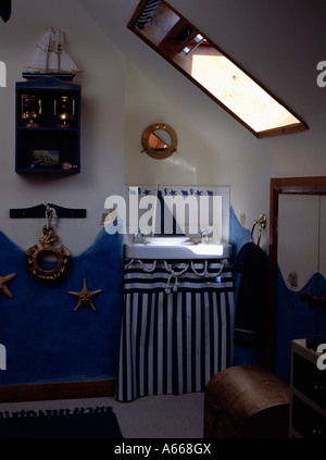 Petite salle de bains grenier sur le thème nautique avec des rideaux à rayures bleues et blanches du bassin ci-dessous Banque D'Images