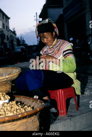 Femme de minorité ethnique Yi en vêtements traditionnels de la vente d'arachides dans les rues de Yuanyang, Yunnan, Chine Banque D'Images