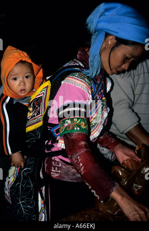 Scène de nuit : femme de minorité ethnique Yi en costume traditionnel, portant son enfant sur le dos. Yunnan, YuanYang. Chine Banque D'Images