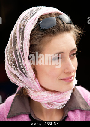 Portrait of Girl woman wearing écharpe rose et Ray Ban lunettes de soleil avec un arrière-plan foncé rose à la mode plus de combinaison de couleurs marron Banque D'Images