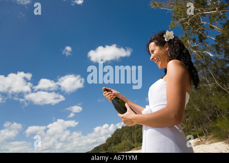 Une femme pop le liège sur une bouteille de champagne de fête Banque D'Images