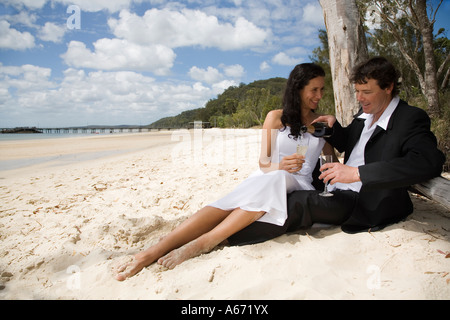 Un couple de profiter d'un verre sur la plage à Kingfisher Bay sur l'île Fraser Banque D'Images