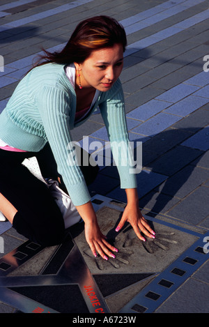 Une femme met ses mains dans les empreintes de Jackie Chan à Hong Kong's Avenue of the Stars Banque D'Images