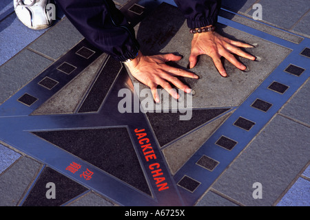 Un visiteur essaie l'impressions de main film star Jackie Chan à Hong Kong's Avenue of the Stars sur le front de mer de Kowloon Banque D'Images