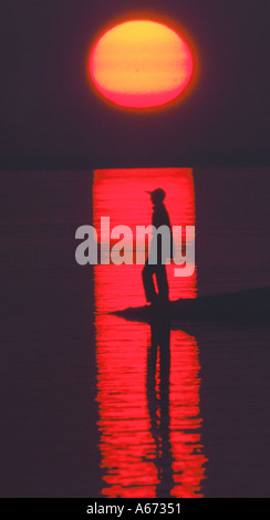 Femme à la plage au coucher du soleil Banque D'Images