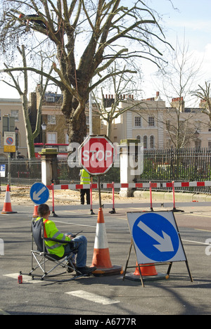 Londres s'asseoir sur le concept d'idées de droit ouvrier assis le contrôle de la circulation autour de tree travaille avec stop go board Banque D'Images