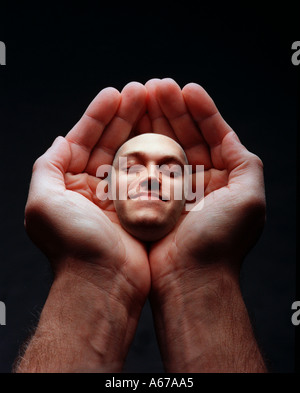 Mains tenant un visage souriant s'homme Banque D'Images