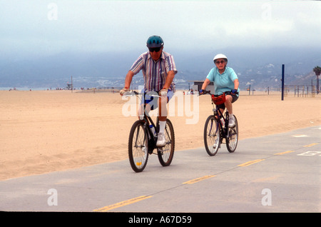 Vieux couple à vélo le long de la plage de Santa Monica, Californie Banque D'Images