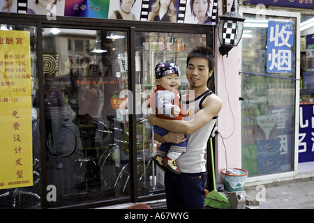 Chine Pékin très jeune père chinois joue avec son fils sur le trottoir en face de la boutique où il a travailler Banque D'Images