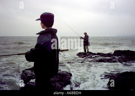 Garçon et l'homme des roches de pêche Banque D'Images