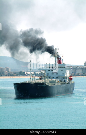 Les navires de fret qui enorment la fumée noire et les émissions de suie de l'entonnoir polluent l'atmosphère et l'environnement locaux arrivant au port de Palma Mallorca Espagne Banque D'Images