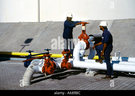 Dubai UAE Oil Terminal de la valve d'arrêt tuyaux travailleurs invités hommes en casque de réservoir de stockage Banque D'Images