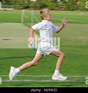 Garçon sprintant dans les sports scolaires course de relais de jour Banque D'Images