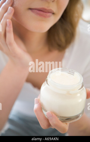 Young woman applying cream Banque D'Images