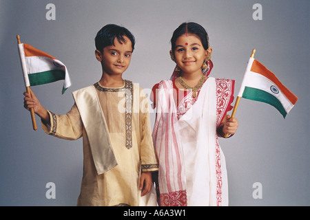 Déguisements enfants Bengali Couple Wearing robes traditionnelles tenant le drapeau indien Banque D'Images