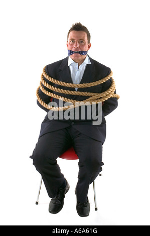 Businessman tied up avec corde et bâillonnée avec sa propre cravate isolé sur fond blanc Banque D'Images