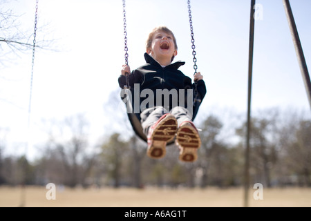Petit enfant sur une balançoire de rire et sourire Banque D'Images
