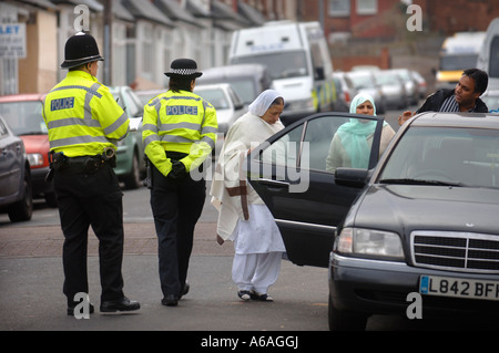 Un policier et une policière PARLER AUX RÉSIDENTS LOCAUX À BIRMINGHAM APRÈS UNE SÉRIE DE RAIDS LIÉES AU TERRORISME JAN 2007 Banque D'Images