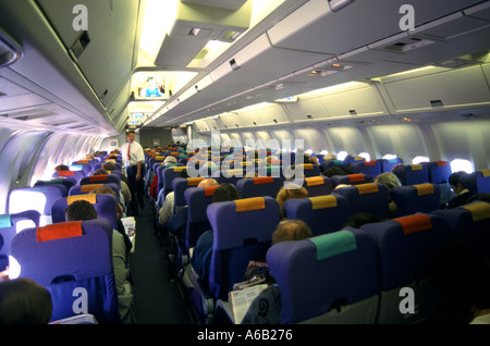 Passagers d'avion dans des sièges dans le steward de vol travaillant l'allée de cabine intérieure d'avion à réaction de vacances dans le vol de vol de l'Angleterre aux Caraïbes Banque D'Images