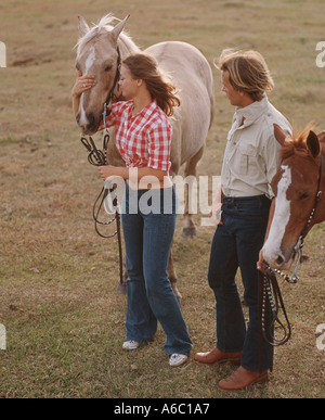 Jeune couple walking horses in field Banque D'Images