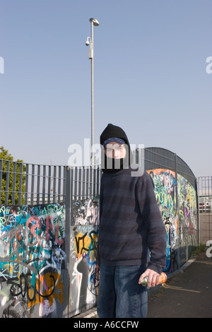 Un jeune à capuchon pulvérise des graffitis et marque son étiquette sur un parc de skate à Southport Merseyside. Banque D'Images