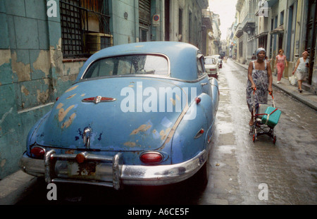 Une femme utilise un bébé buggy pour le transport de l'eau à La Havane Cuba la voiture il est mort est une ère 1950 Buick Banque D'Images