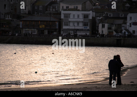 Couple regardant le coucher du soleil sur le port de St Ives en Cornouailles Banque D'Images