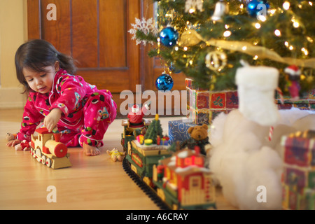 Girl Playing with Toy train le matin de Noël Banque D'Images