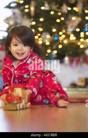 Little Girl Playing with Toy train le matin de Noël Banque D'Images