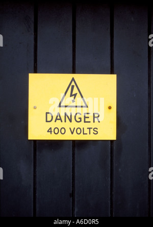 Signe de danger haute tension jaune sur la porte en bois Banque D'Images