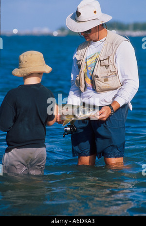 Man showing boy Snook Centropomus dans udecimalis l'Indian River Lagoon Saint Lucie Martin County Florida Estuaire Banque D'Images