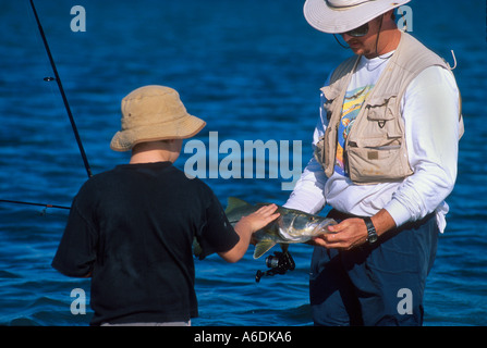 Man showing boy Snook Centropomus dans udecimalis l'Indian River Lagoon Saint Lucie Martin County Florida Estuaire Banque D'Images