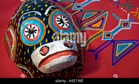 Masque de danse en bois guatémaltèque d'un singe à l'encontre d'un textile Maya en brocart rouge de Chajul hautes terres guatémaltèques Banque D'Images