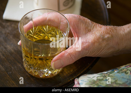 Close up of old ladys main tenant le verre de whisky Banque D'Images