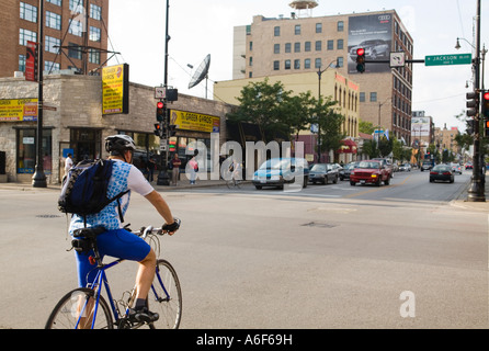 Dans Bicylists Chicago Illinois bike lane Jackson Boulevard et Halsted street intersection homme cycliste avec sac à dos Banque D'Images