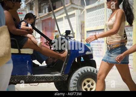 BELIZE San Pedro sur Ambergris Caye on marche par woman holding baby sur tour en scène de rue de chariot de golf Banque D'Images