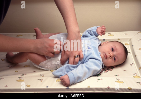 Bébé garçon de cinq semaines ayant la couche de couche changée à l'intérieur gros plan des mains de la mère avec le modèle d'anneau de mariage releases1947 image d'archive Angleterre Royaume-Uni Banque D'Images