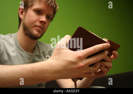 Jeune homme blond lire la Bible avec fond vert lumineux Banque D'Images