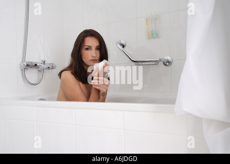 Brunette woman-baignoire, juste avant de sucer de sa main en mousse Banque D'Images