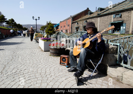 Musicien ambulant qui joue de la guitare à côté de fameux canal dans Otaru Japon 2005 Banque D'Images