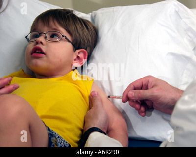 Jeune garçon regarde ailleurs lors de l'obtention d'une vaccination en milieu libre Banque D'Images