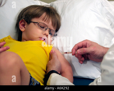 Jeune garçon regarde nerveusement mais courageusement lors de la réception d'une vaccination en milieu libre Banque D'Images