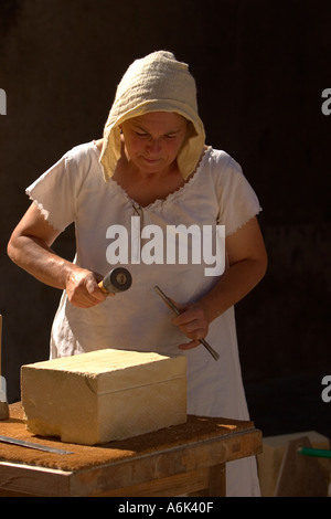 Femme française Stonemason, sculpteur de pierre en costume d'époque français sculptant de pierre avec outils à main au festival médiéval, Aquitaine Sud-Ouest France ue Banque D'Images