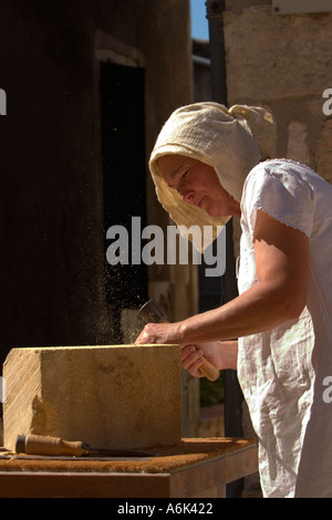 Femme française Stonemason, sculpteur de pierre en costume d'époque français sculptant de pierre avec outils à main au festival médiéval, Aquitaine Sud-Ouest France ue Banque D'Images