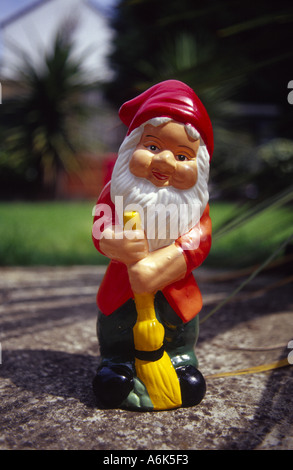 Nain de jardin avec un ramonage dans un jardin de banlieue sur une journée ensoleillée Banque D'Images