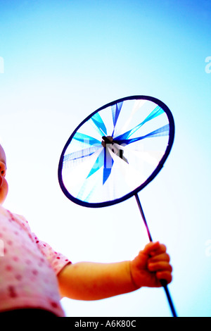 Petit bébé tenant une windwheel dans le ciel Banque D'Images