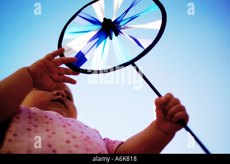 Petit bébé tenant une windwheel dans le ciel Banque D'Images