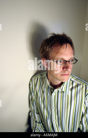 Portrait d'un homme en chemise rayée il a les cheveux blonds et porte des petites lunettes Lunettes encadrées en plastique noir Banque D'Images