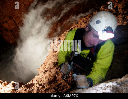 Un spéléologue britannique marteaux dans un autre boulon pour faire de cette immense chute d'eau souterraine grimper en sécurité Banque D'Images