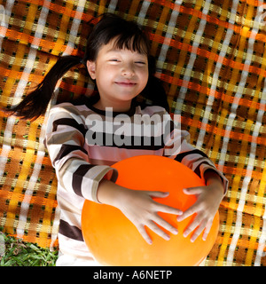 Girl (8-9) holding balloon, lying on picnic blanket, overhead view Banque D'Images